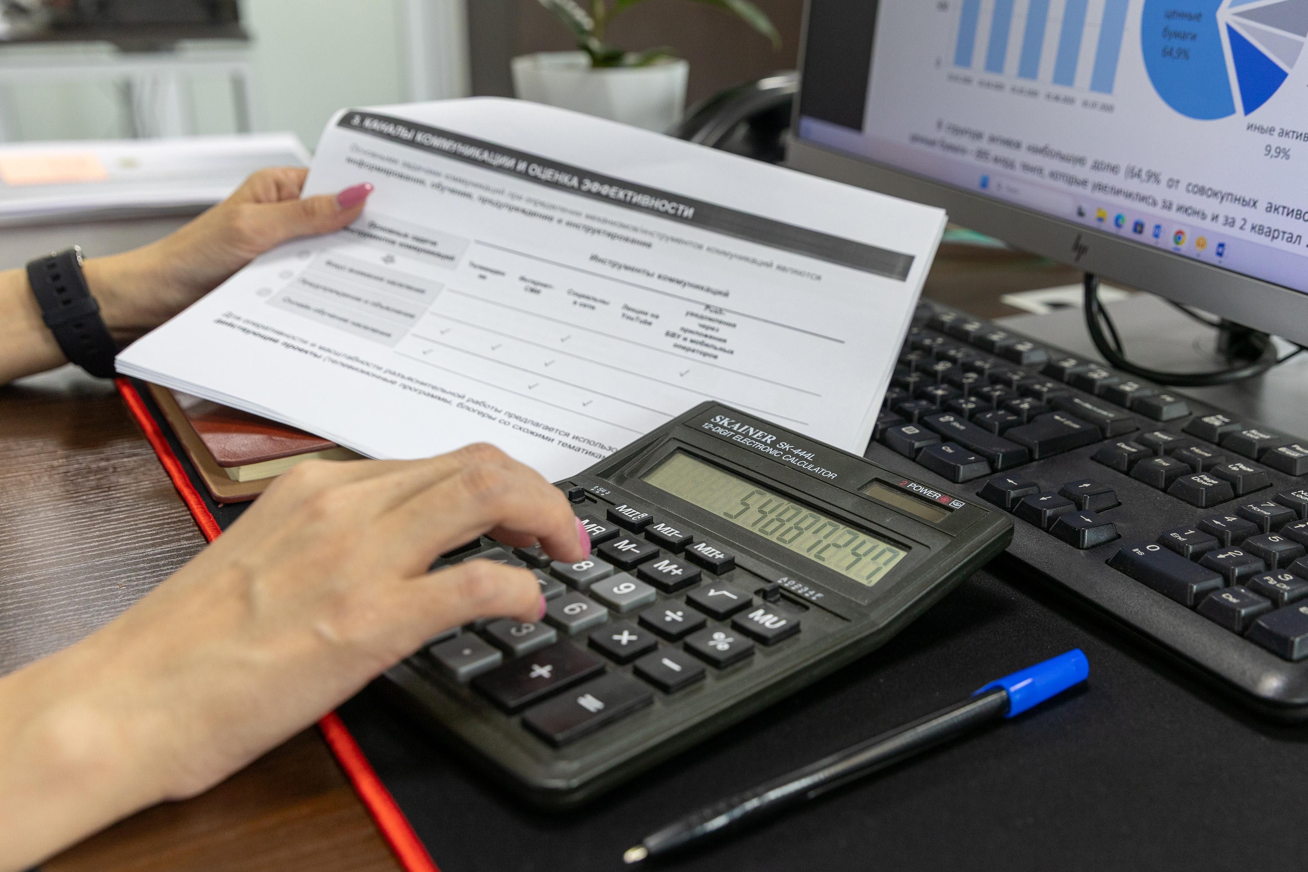 Fotografía ilustrativa de una persona trabajando con una calculadora, documentos y gráficos en una oficina. Imagen de banco; no muestra las jornadas del CPCE ni una empresa de San Juan.