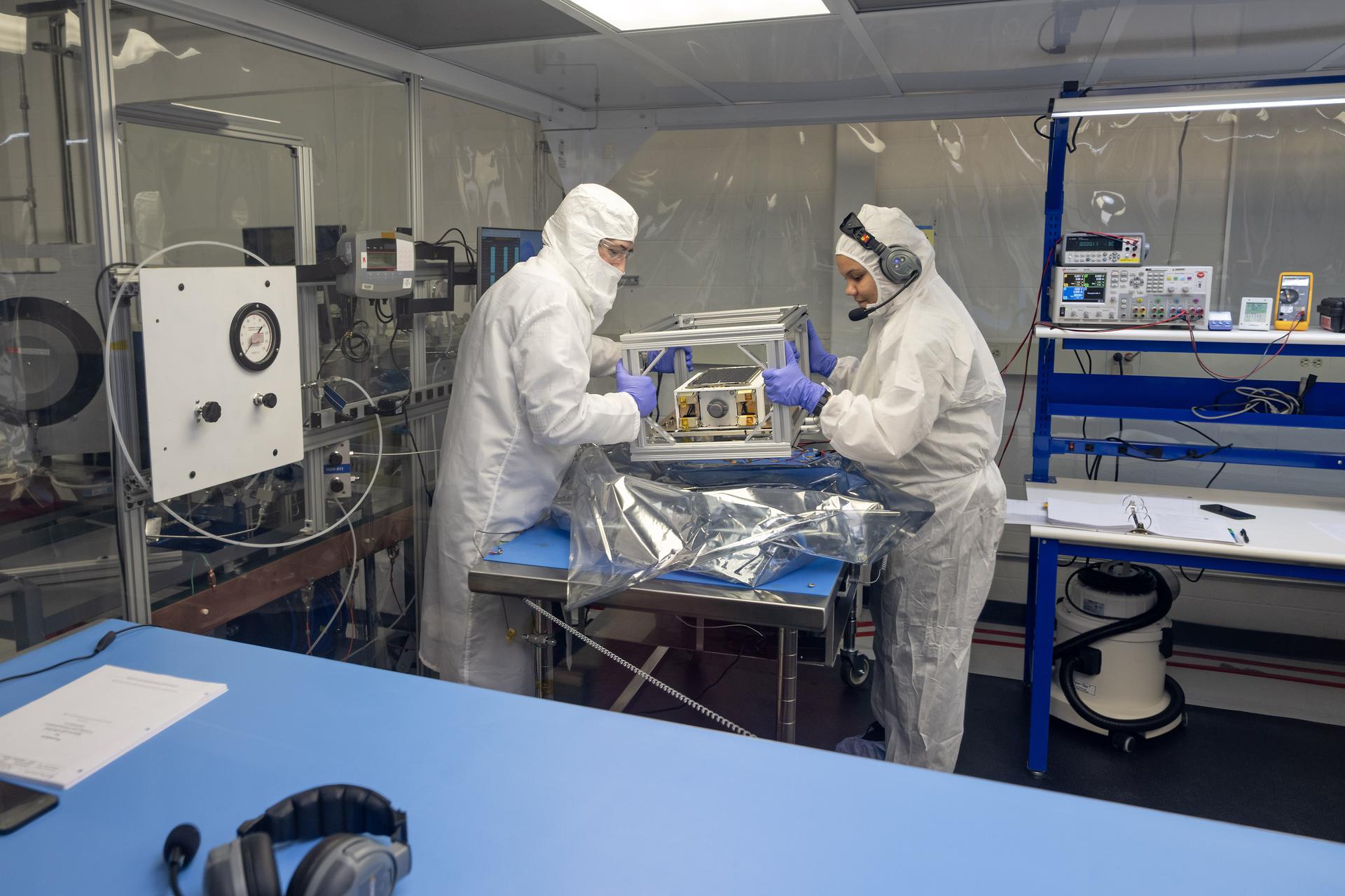 Chris Burnside y Ebony Bland preparan el pequeño satélite ASCENT para pruebas en una sala limpia del Centro Marshall, antes de su lanzamiento.