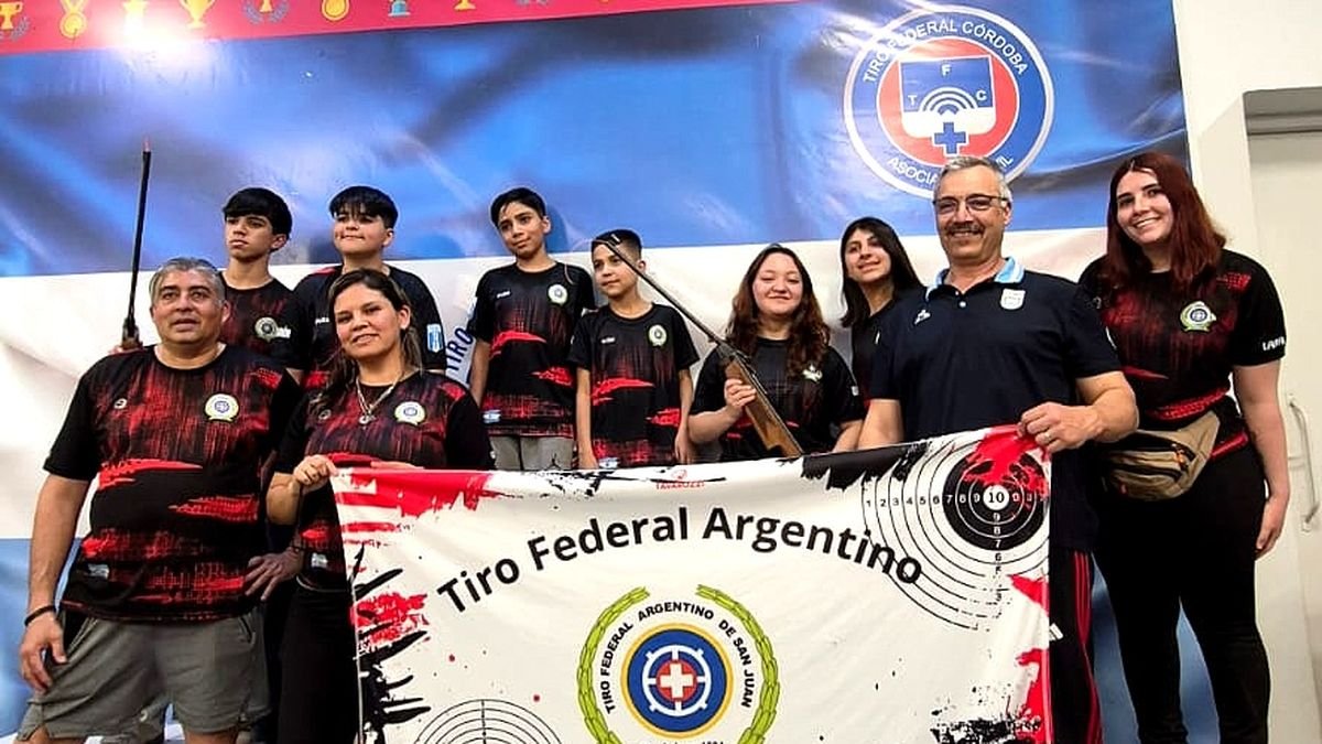 Integrantes de una delegación de tiro deportivo con una bandera del Tiro Federal Argentino.