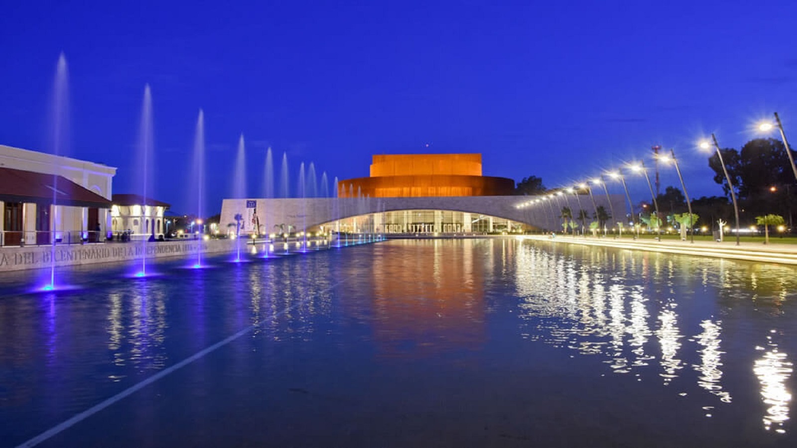 Vista nocturna de archivo del exterior del Teatro del Bicentenario, con su fuente iluminada. Fecha de toma no informada. Ilustra el complejo donde se realizará el concierto; no muestra a Cuidado Marvin! ni el interior de la Sala Auditórium. Fotografía íntegra, reducida proporcionalmente de 1920×1080 a 1600×900, sin recorte ni retoque.