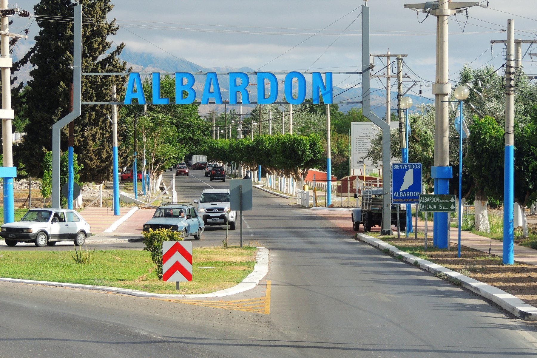 Entrada vial de Albardón con el cartel del departamento y vehículos; fotografía de archivo de noviembre de 2013.