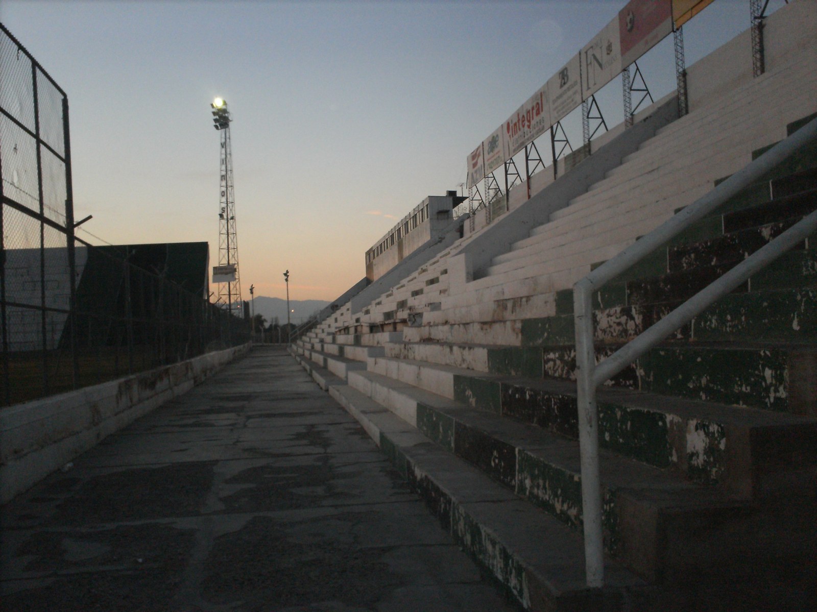 Tribunas vacías verdes y blancas del estadio Ingeniero Hilario Sánchez, fotografiadas al atardecer en 2011.
