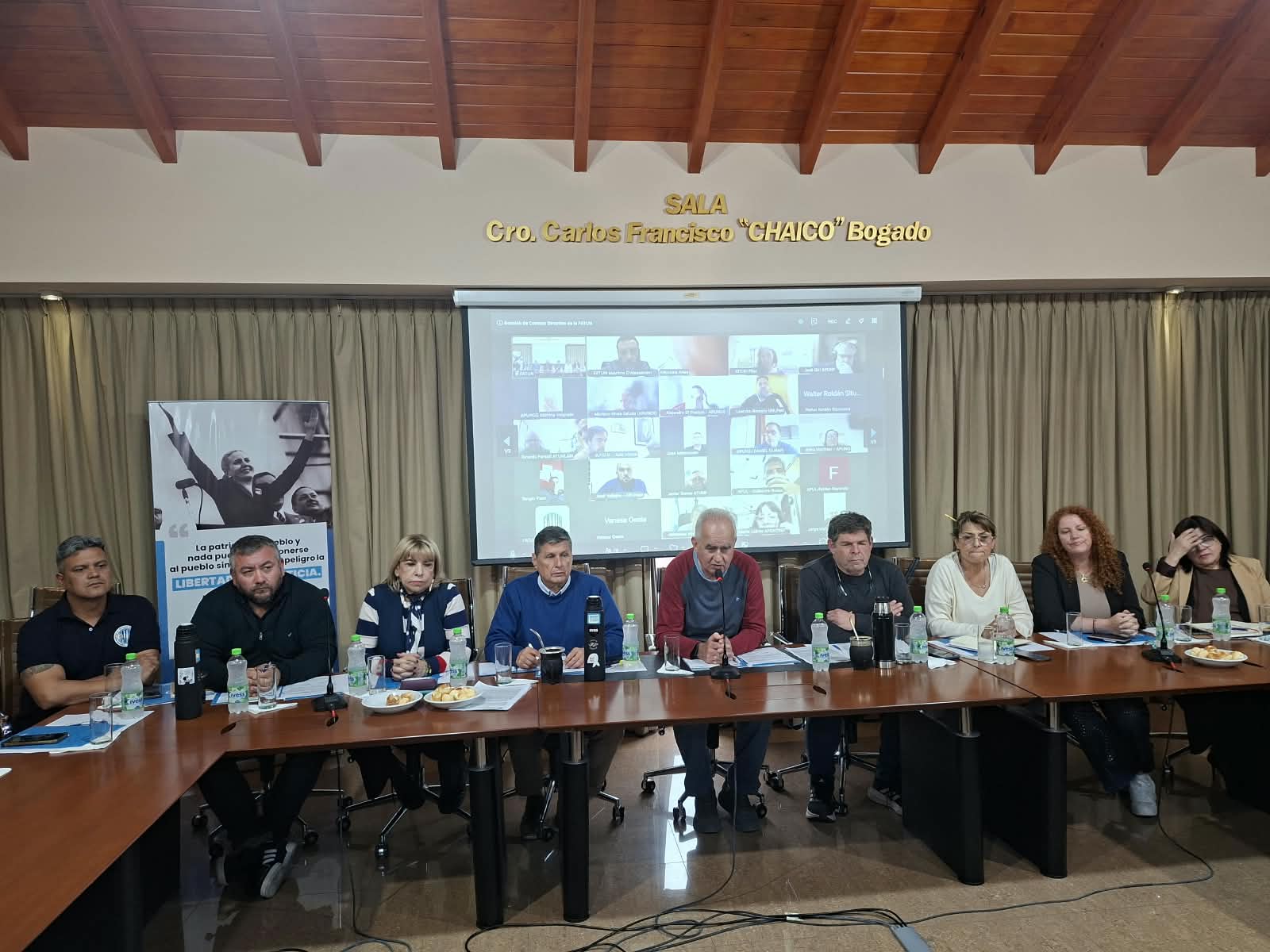Integrantes del Consejo Directivo de FATUN en la reunión híbrida del 21de octubre de 2026, con participantes remotos proyectados detrás. Foto del encuentro en que se aprobó el calendario de paros, no de una huelga ya realizada.