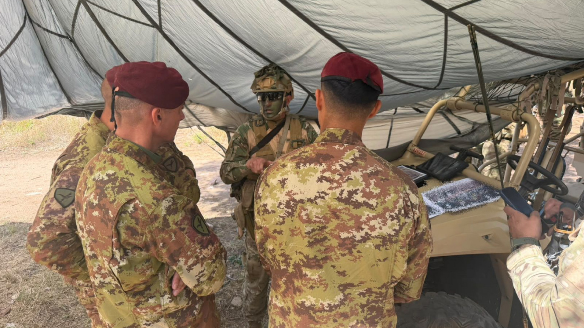 Militares argentinos e italianos reunidos junto a equipamiento bajo una carpa durante el ejercicio Pegaso 5.