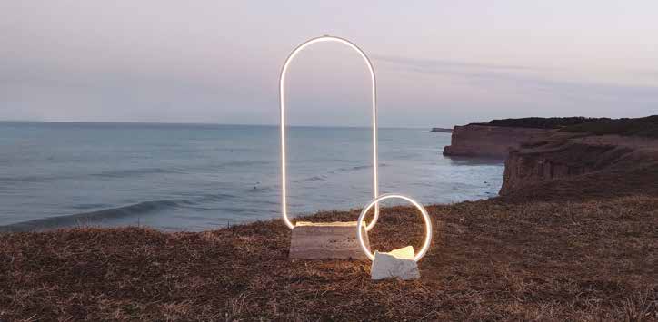Dos lámparas Acantilados, diseñadas por Paz Cano y Santiago Rolón, sobre bases de piedra frente al paisaje costero de Mar del Plata. Foto de producto del catálogo SBD 13, anterior a la exhibición de Barcelona 2026.