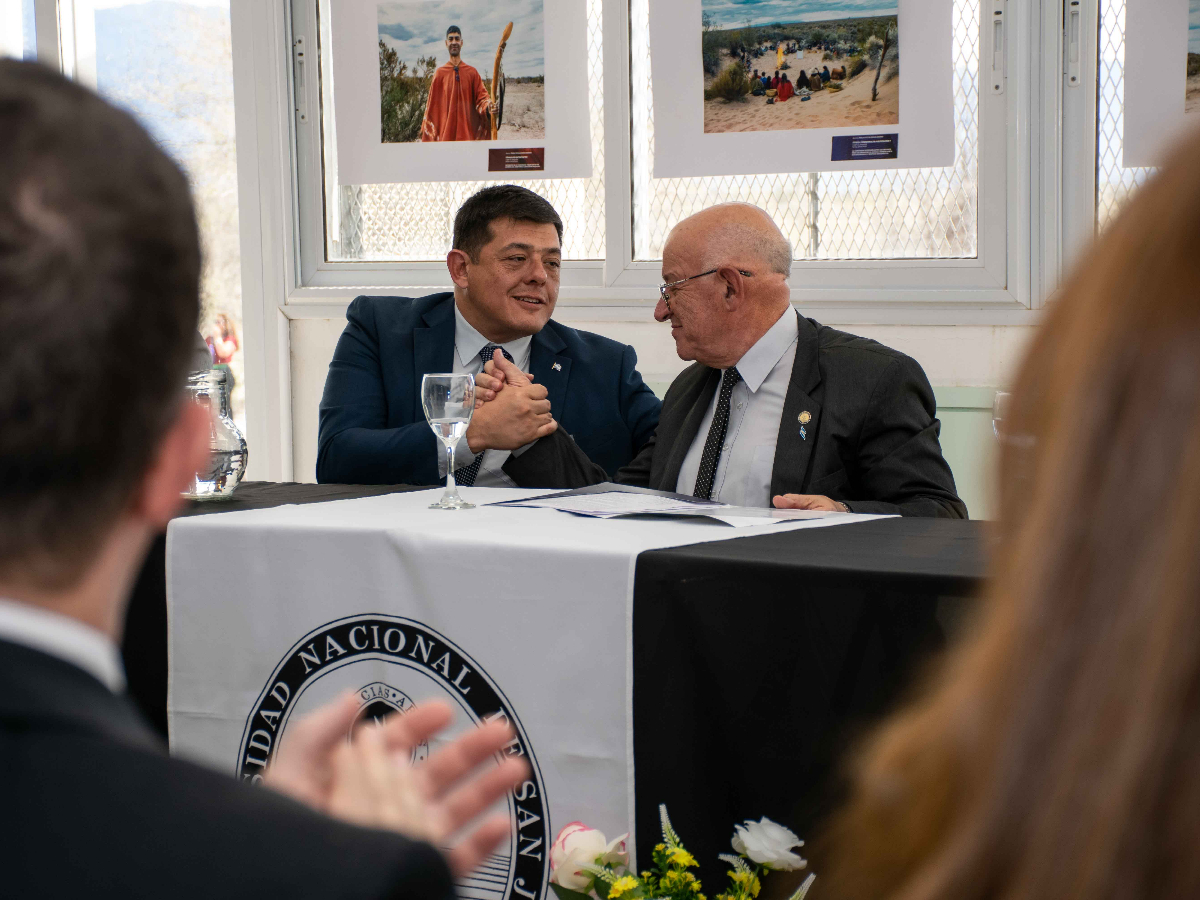 Matías Espejo y Tadeo Berenguer se saludan en una mesa de la UNSJ; fotografía difundida por la Universidad junto con el anuncio del acta complementaria para la sede Jáchal.