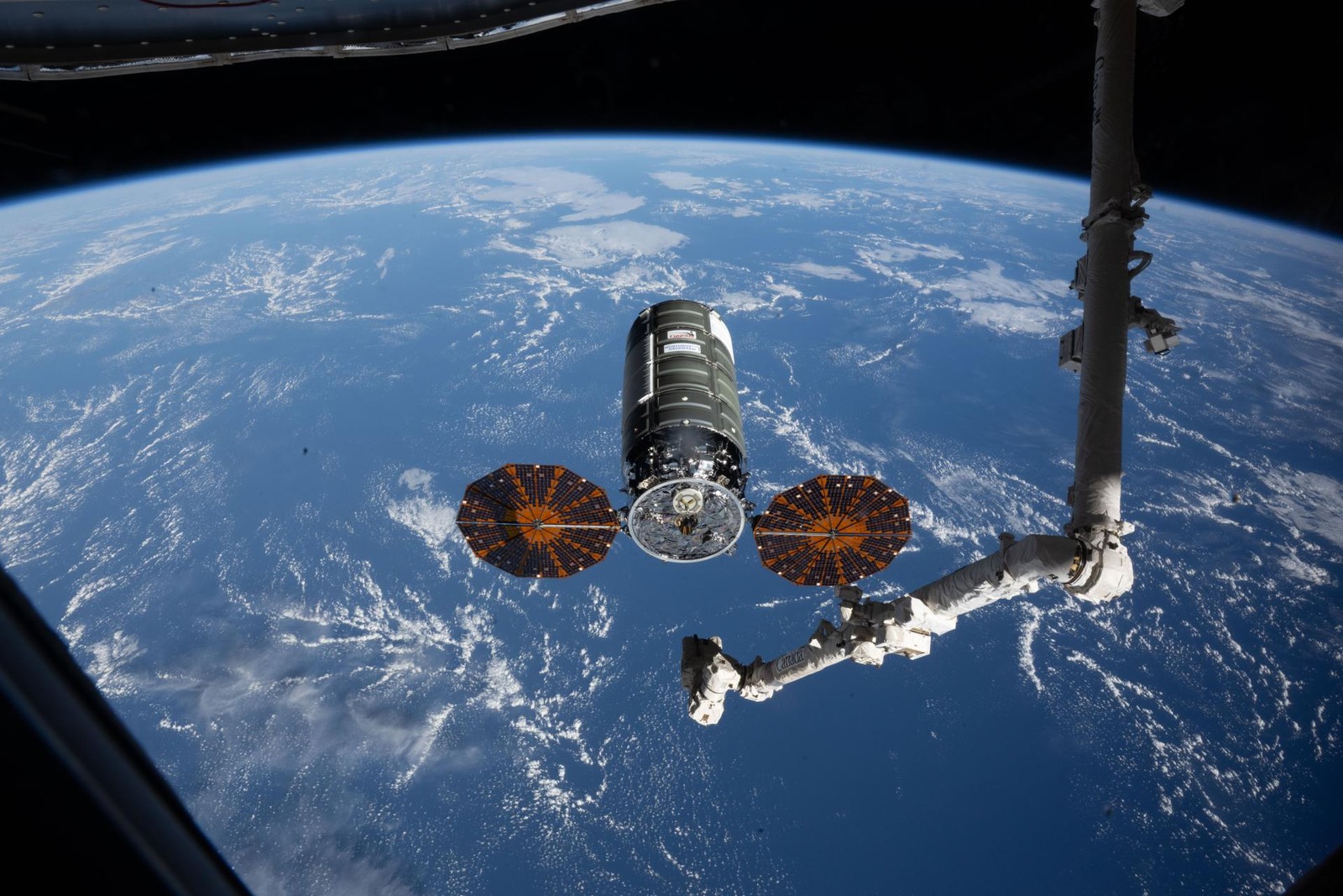 Cygnus XL frente a la Tierra y el brazo Canadarm2, a doce metros de la Estación Espacial Internacional durante su llegada el 13 de abril de 2026.