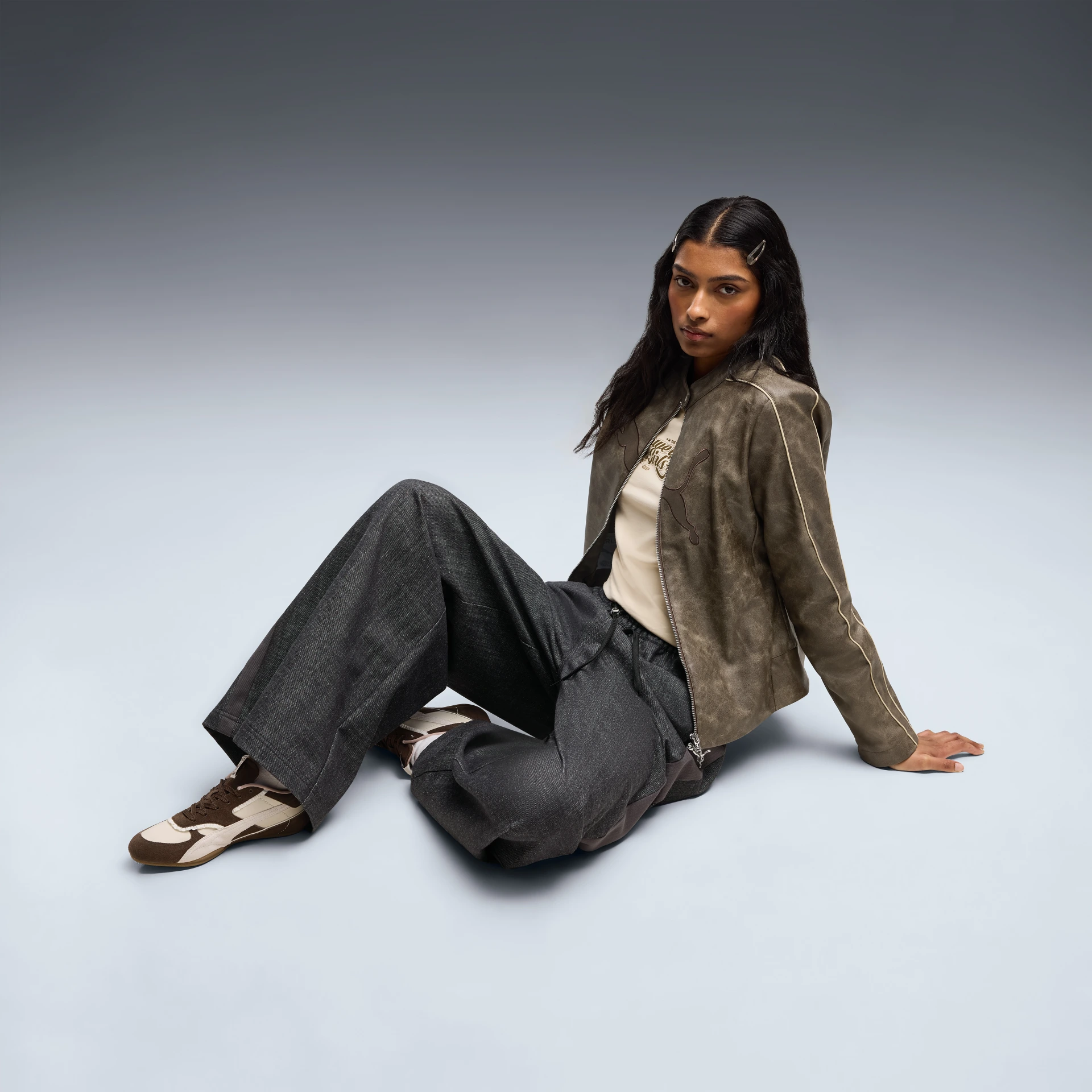 Modelo con campera marrón, pantalones amplios y zapatillas Bella Mina de la colección Puma x The Powerpuff Girls. Fotografía oficial de la cápsula lanzada globalmente el 1 de octubre de 2026.
