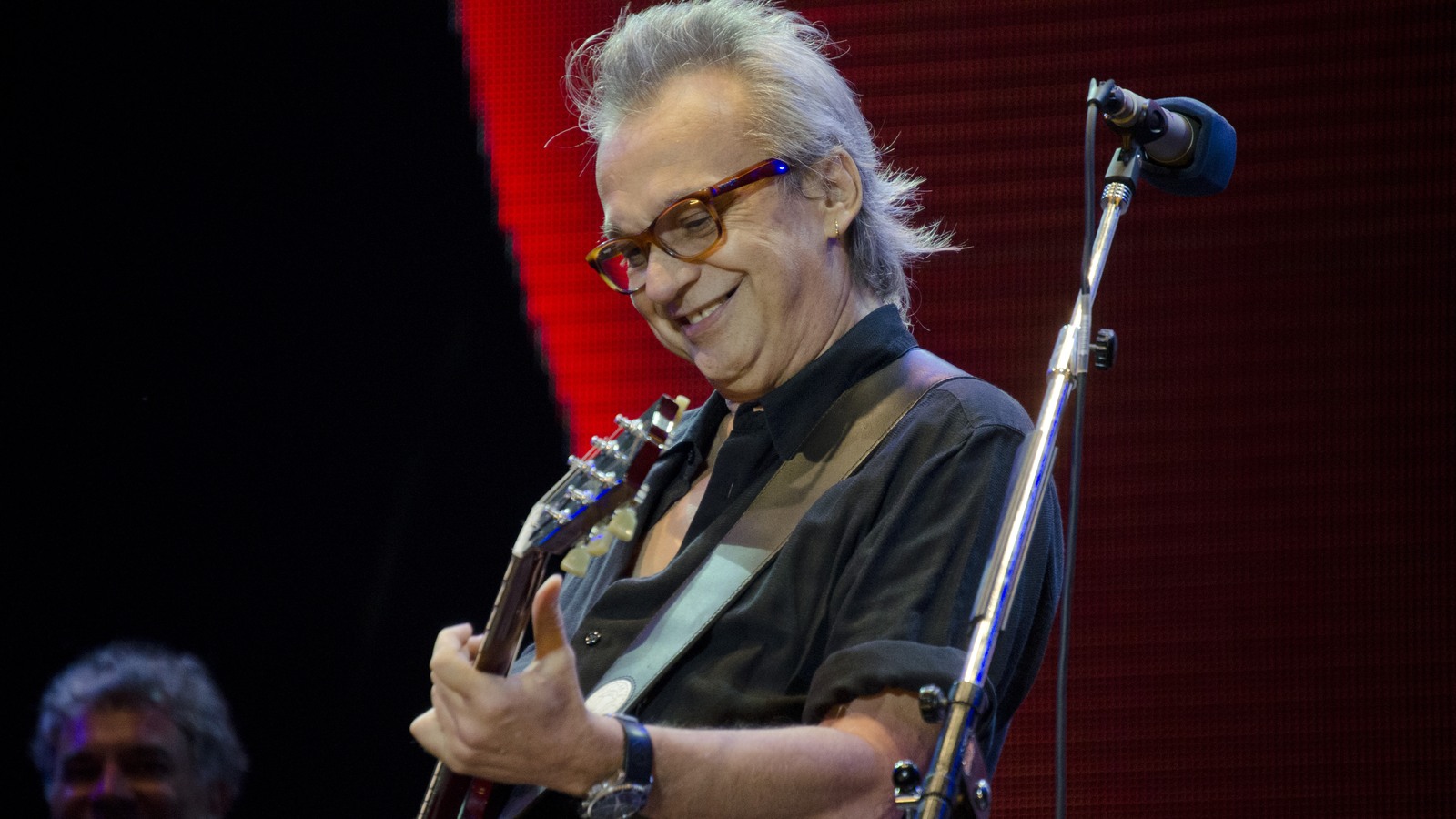 David Lebón toca la guitarra frente a un micrófono. Fotografía de archivo de 2013; no corresponde a las funciones futuras de San Juan.