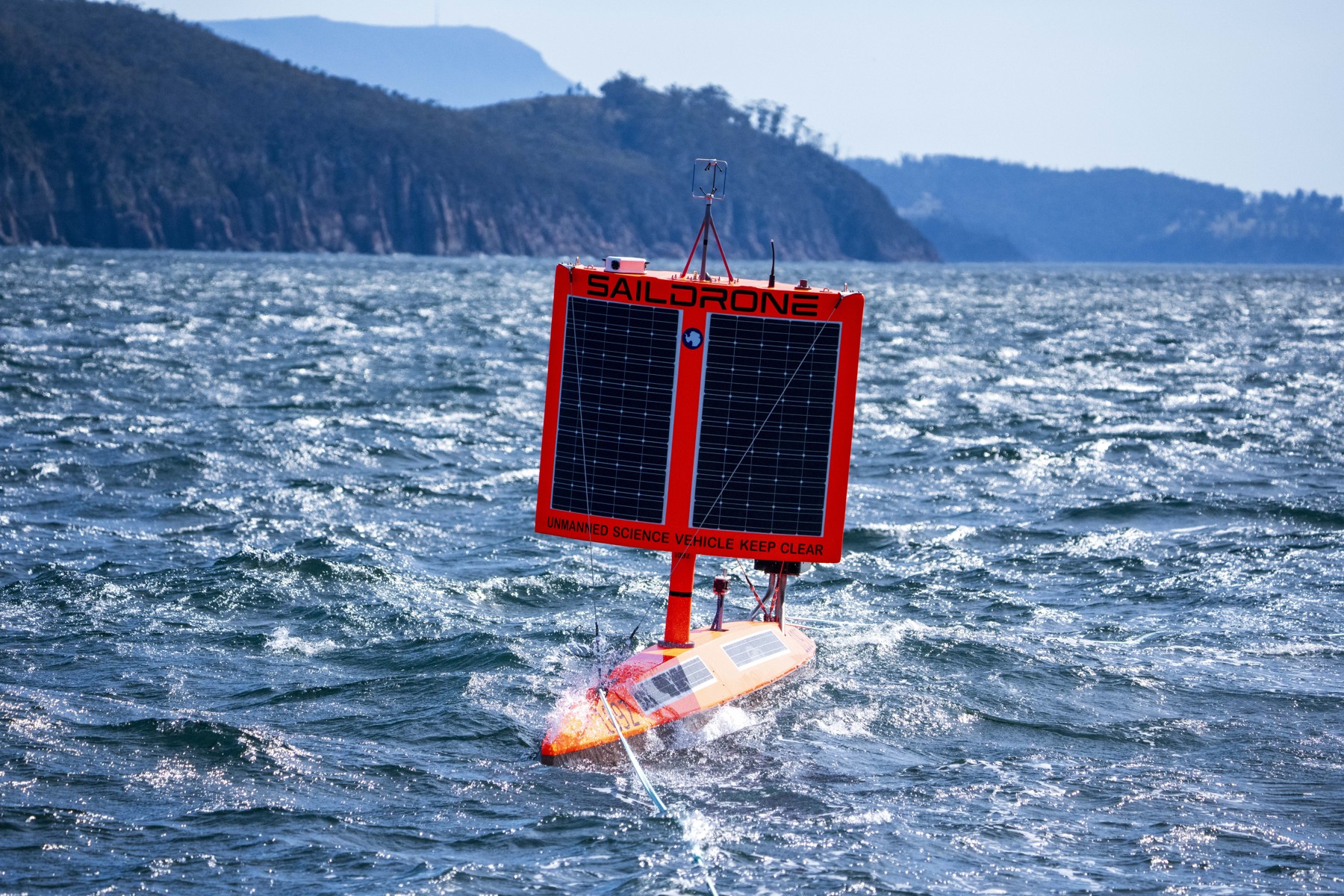 Un Saildrone rojo es remolcado en aguas de Hobart al comienzo de la campaña científica de septiembre de 2026.