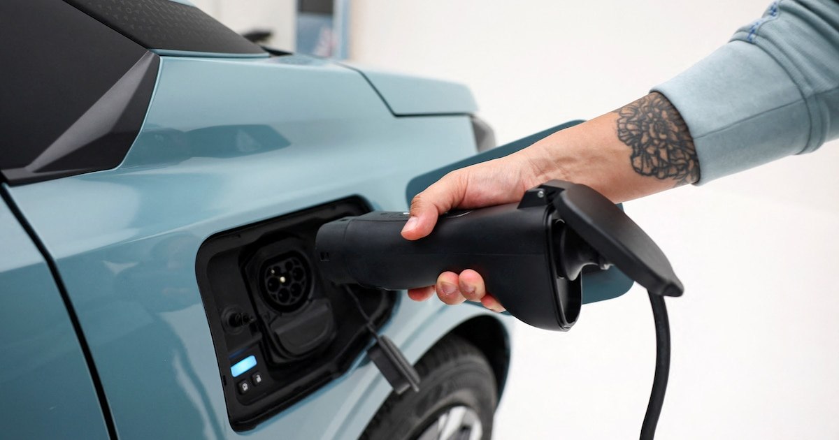 Una persona conecta un vehículo eléctrico a un punto de carga.