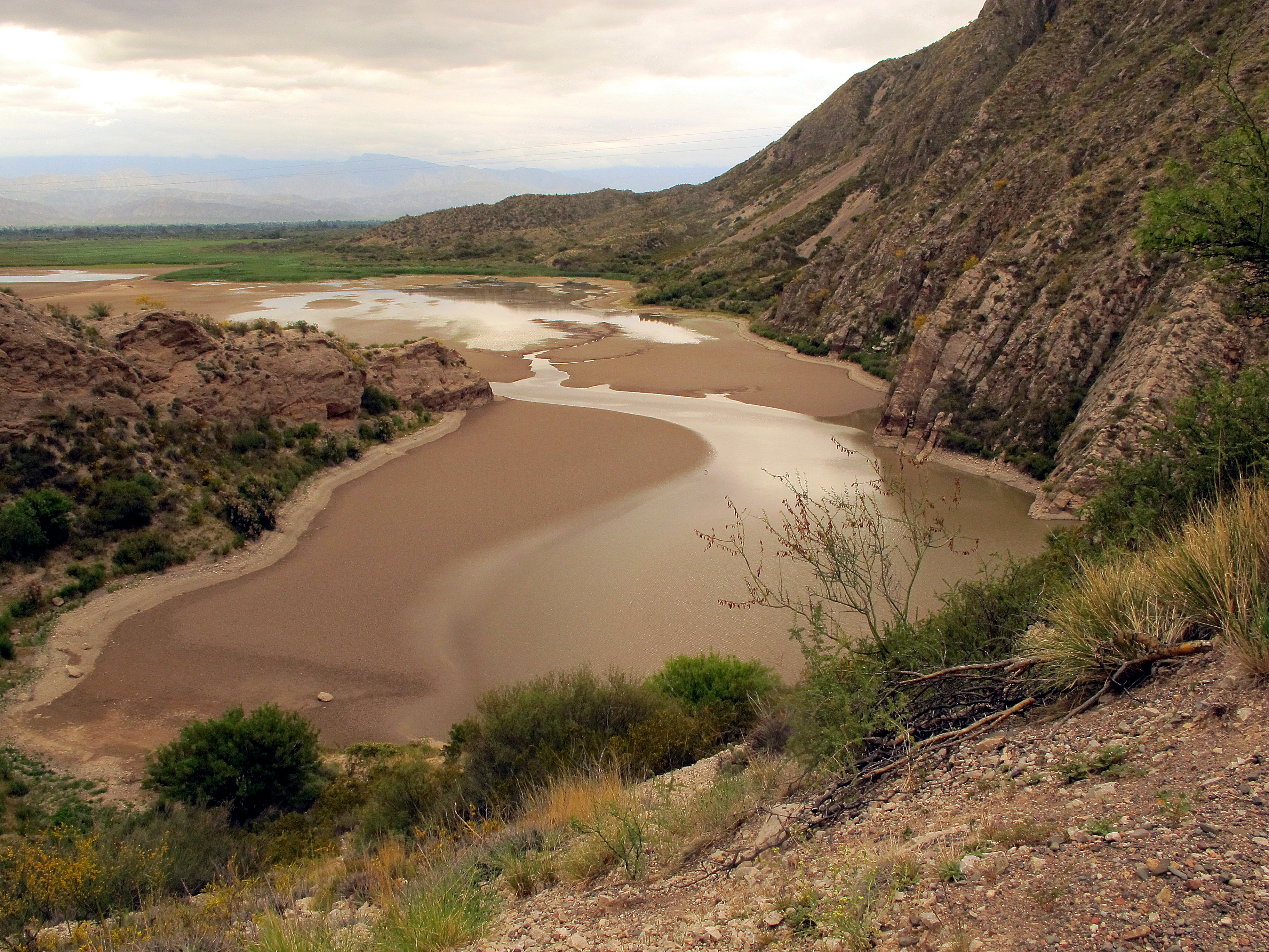 Vista de La Ciénaga desde la Cuesta de Huaco, en Jáchal: agua entre sedimentos y laderas rocosas. Fotografía de archivo del 29 de noviembre de 2015, anterior a la campaña científica de octubre de 2026.