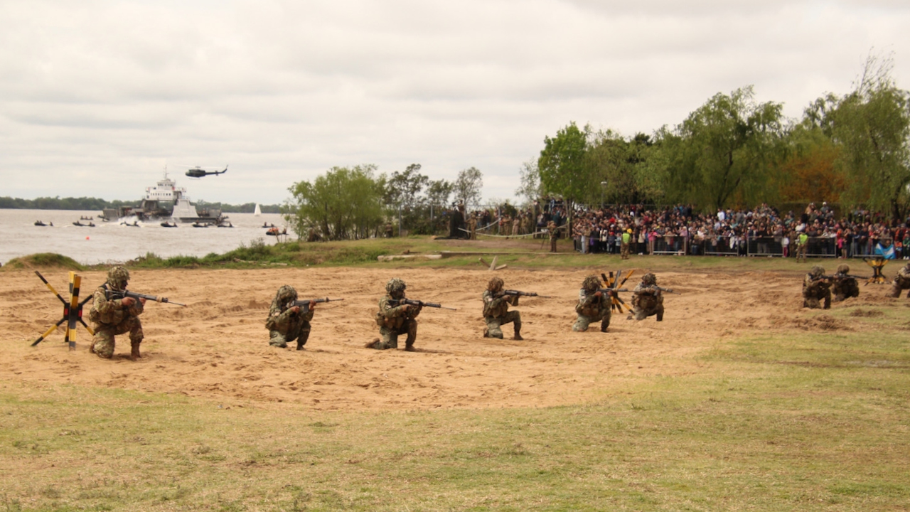 Militares durante el ejercicio Biguá en la ribera del Paraná, con embarcaciones, un helicóptero y público al fondo. Rosario, 3 de octubre de 2026.