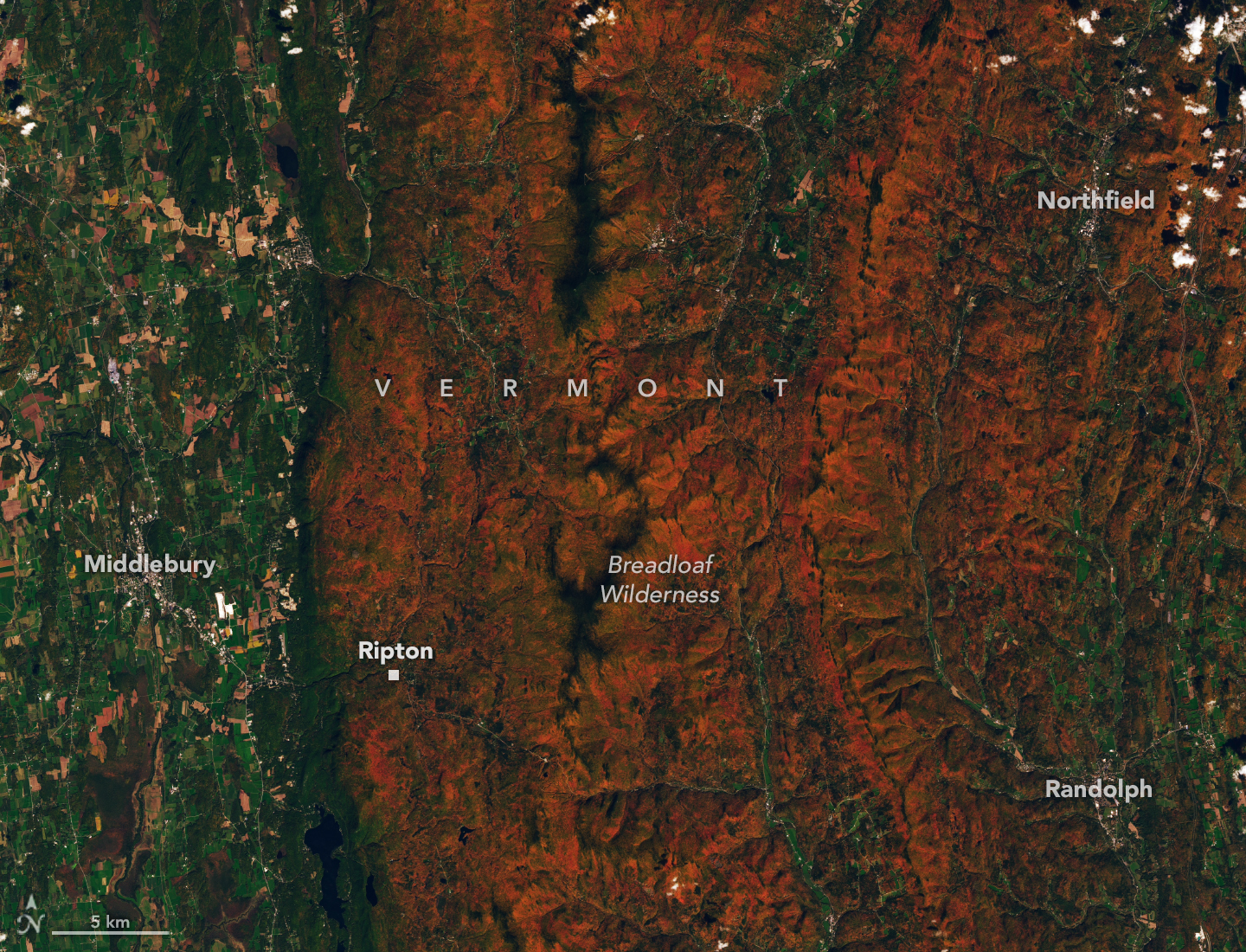 Observación de Landsat 9 del 3 de octubre de 2026: bosques rojizos y anaranjados alrededor de Ripton, Vermont, con valles verdes. La imagen satelital lleva rótulos geográficos originales de NASA Earth Observatory; no es una toma de hoy ni de San Juan.