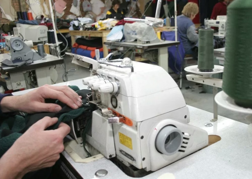 Máquinas de coser y personas trabajando en un taller textil. Fotografía de archivo publicada por Diario de Cuyo.