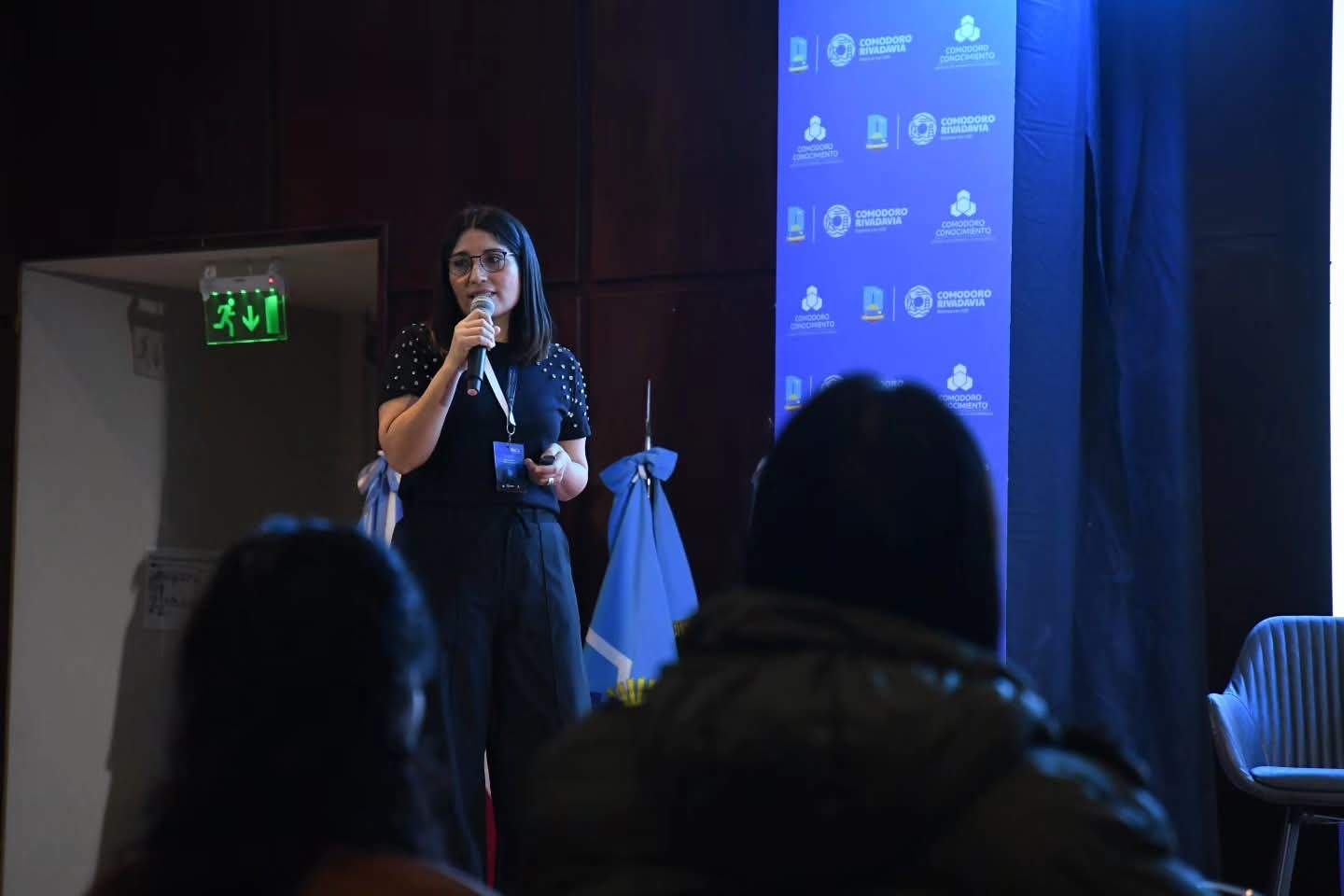 Natalia Rementería expone con un micrófono ante el público en la 12.ª Exposición Industrial y Comercial de Comodoro Rivadavia.