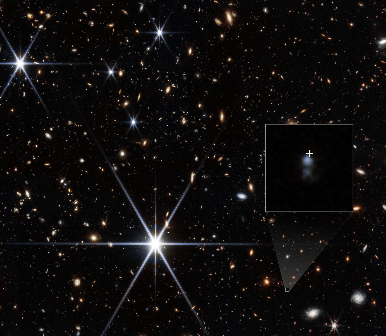 Imagen observacional infrarroja de NIRCam con una ampliación de la galaxia anfitriona de FRB 20240304B. La cruz blanca marca la posición de la ráfaga; no es una fotografía del destello de radio.