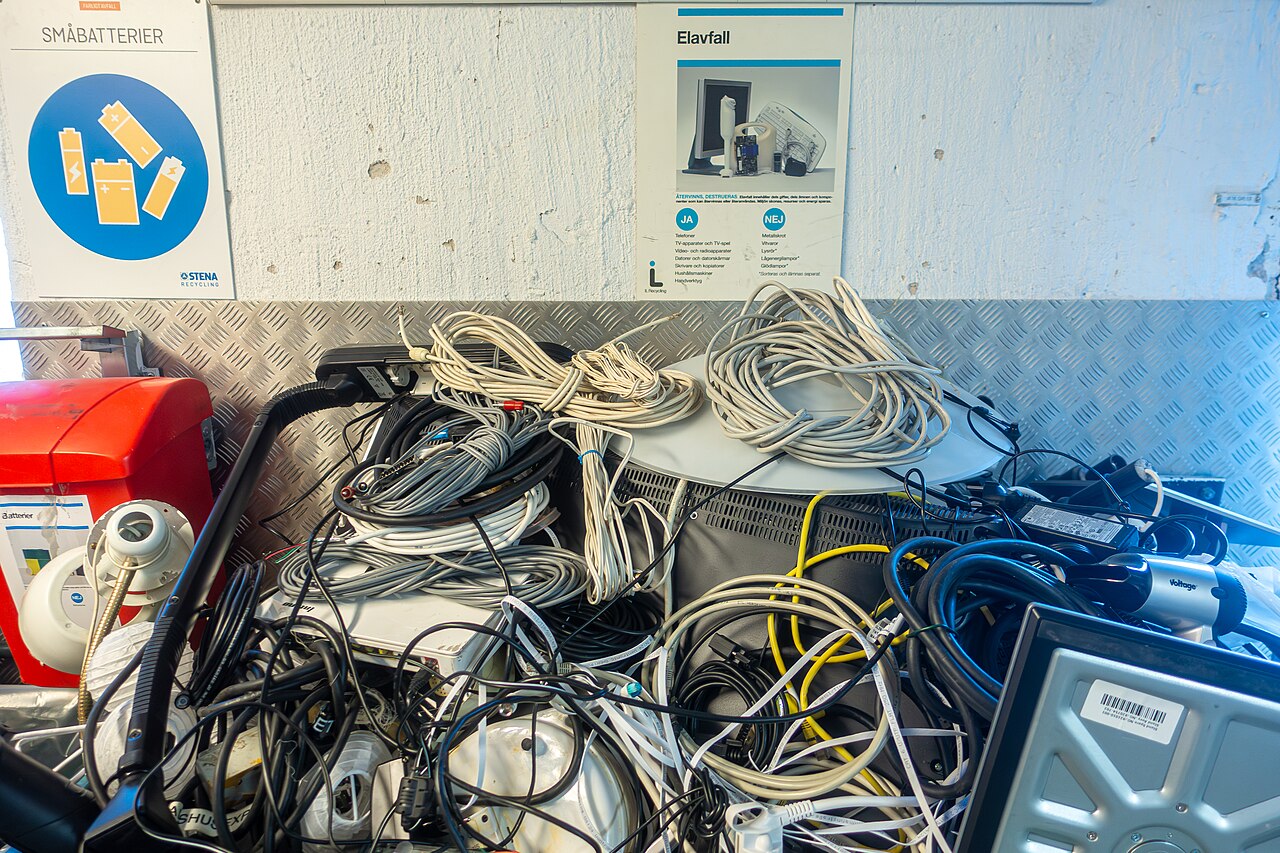 Equipos, cables y otros residuos electrónicos en un contenedor de una cooperativa de vivienda en Suecia, febrero de 2026. Imagen de archivo, ajena a la campaña del Colegio Central.