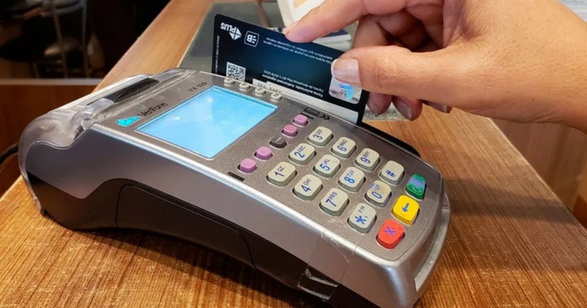 Una persona acerca una tarjeta a una terminal de pago en un comercio.