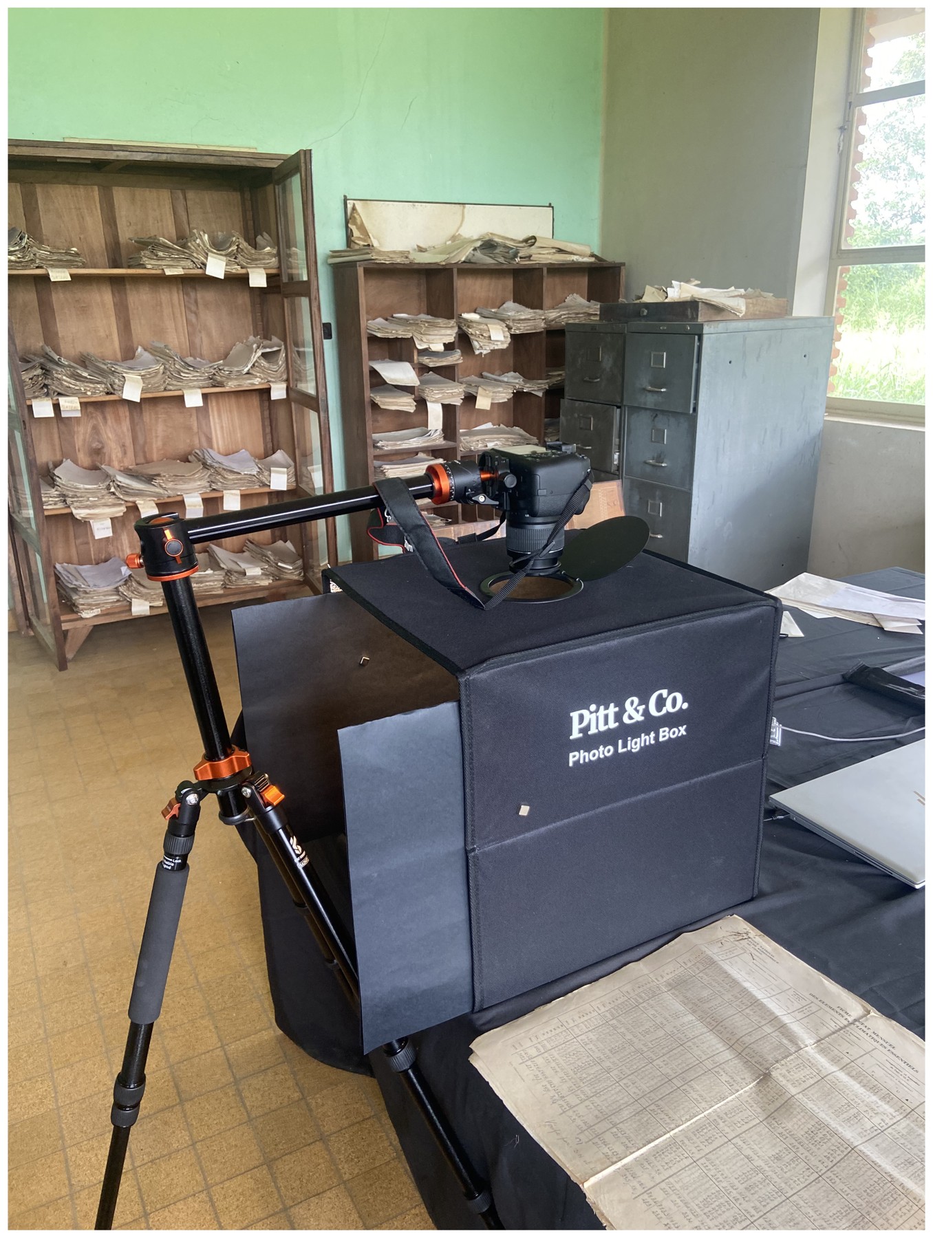 Equipo utilizado para fotografiar archivos meteorológicos históricos en INERA, Yangambi: cámara, trípode, caja de iluminación y planillas. Fotografía de la campaña del 15 de agosto de 2023 publicada como figura 5 del estudio.