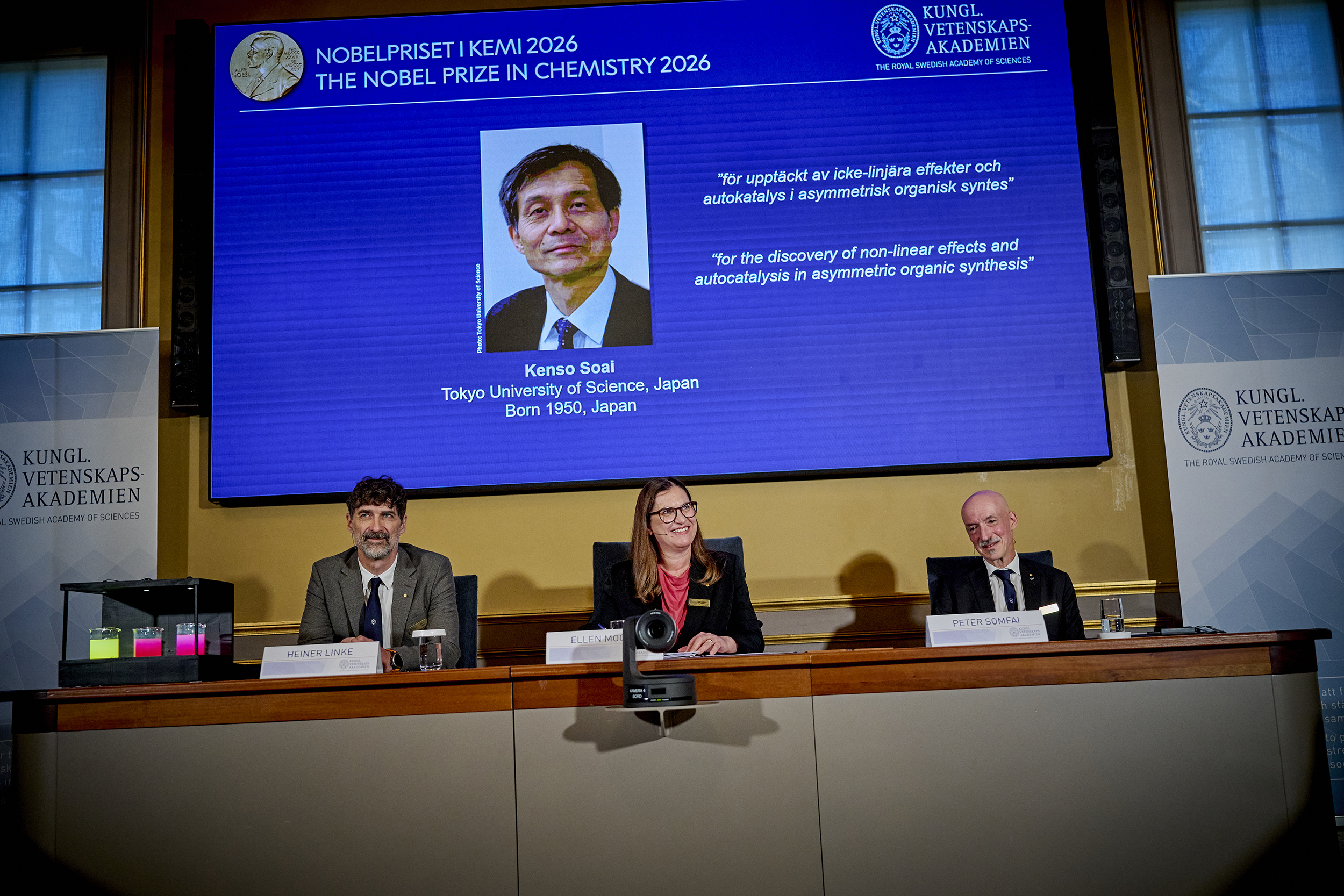 Heiner Linke, Ellen Moons y Peter Somfai durante el anuncio del Nobel de Química 2026 en Estocolmo. La pantalla muestra el retrato de Kenso Soai y la motivación del premio.