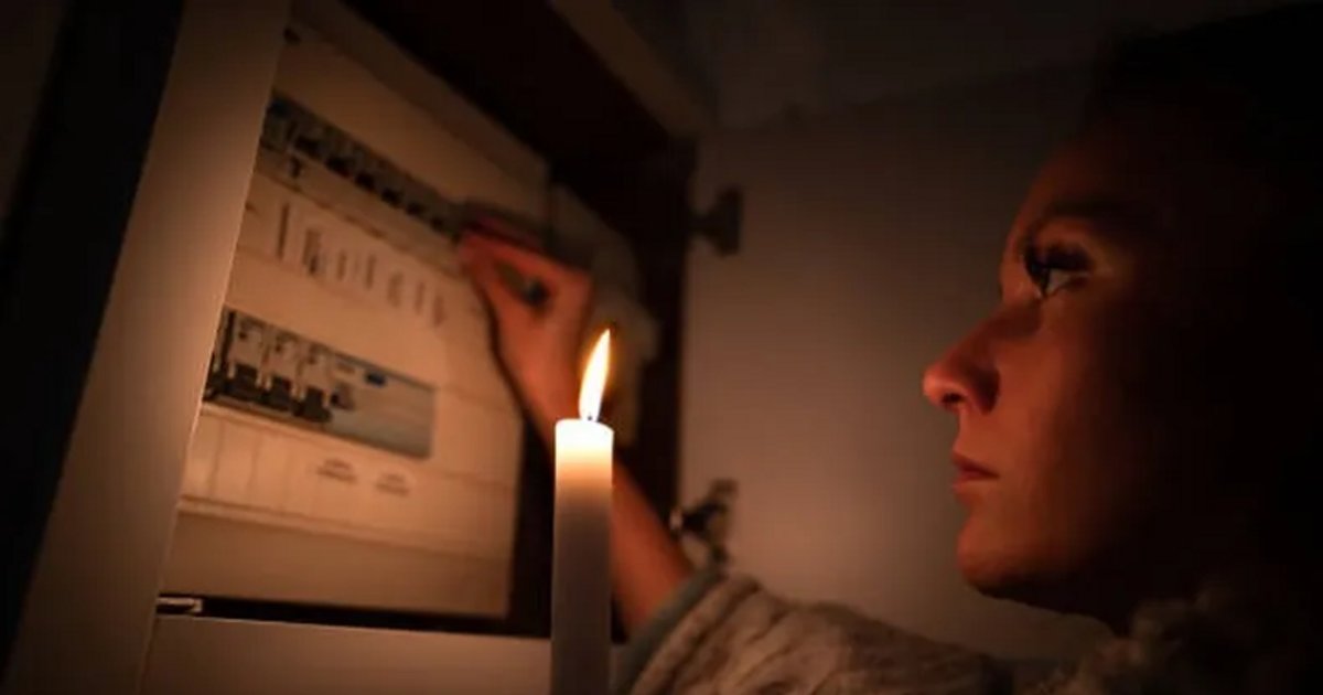 Una persona junto a un tablero eléctrico iluminado con una vela; imagen ilustrativa.