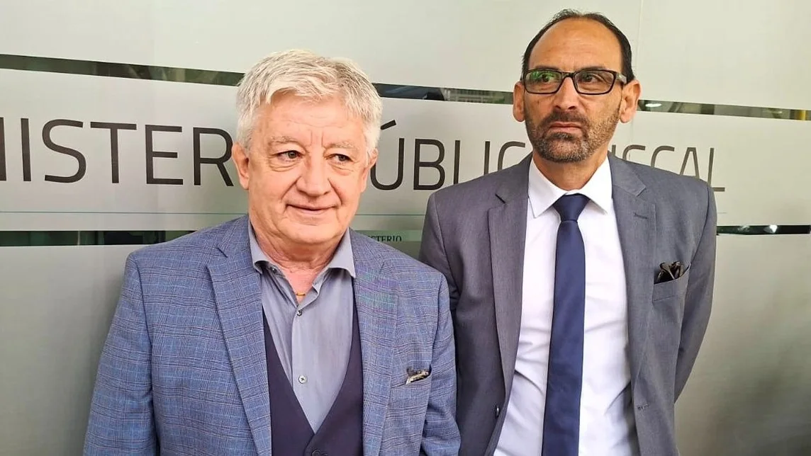 Fotografía de archivo de Roberto Mallea junto a otro funcionario, frente a un cartel del Ministerio Público Fiscal.