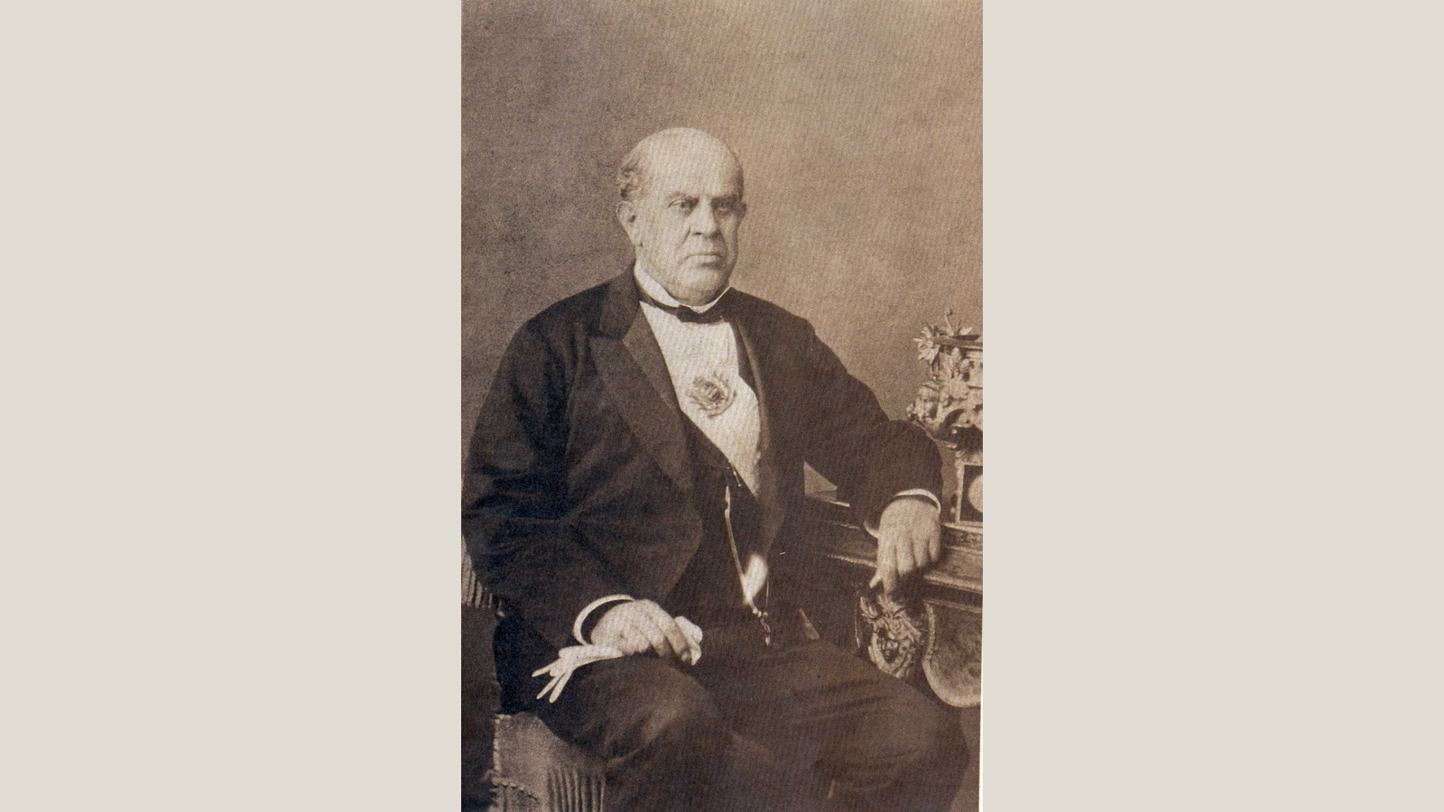 Domingo Faustino Sarmiento sentado con banda presidencial, en un retrato fotográfico de Christiano Junior de 1873, conservado por el Archivo General de la Nación. Fotografía histórica, no corresponde al conversatorio de 2026. Imagen íntegra, reducida proporcionalmente y presentada con márgenes neutros a 16:9, sin recorte.