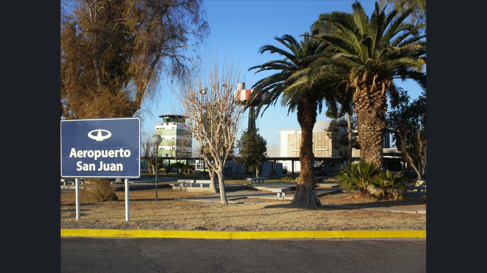 Acceso al Aeropuerto Domingo Faustino Sarmiento de San Juan, con cartel identificatorio, torre de control y antigua terminal. Foto de archivo de 2011. Presentación 16:9 con fotografía completa y márgenes neutros.